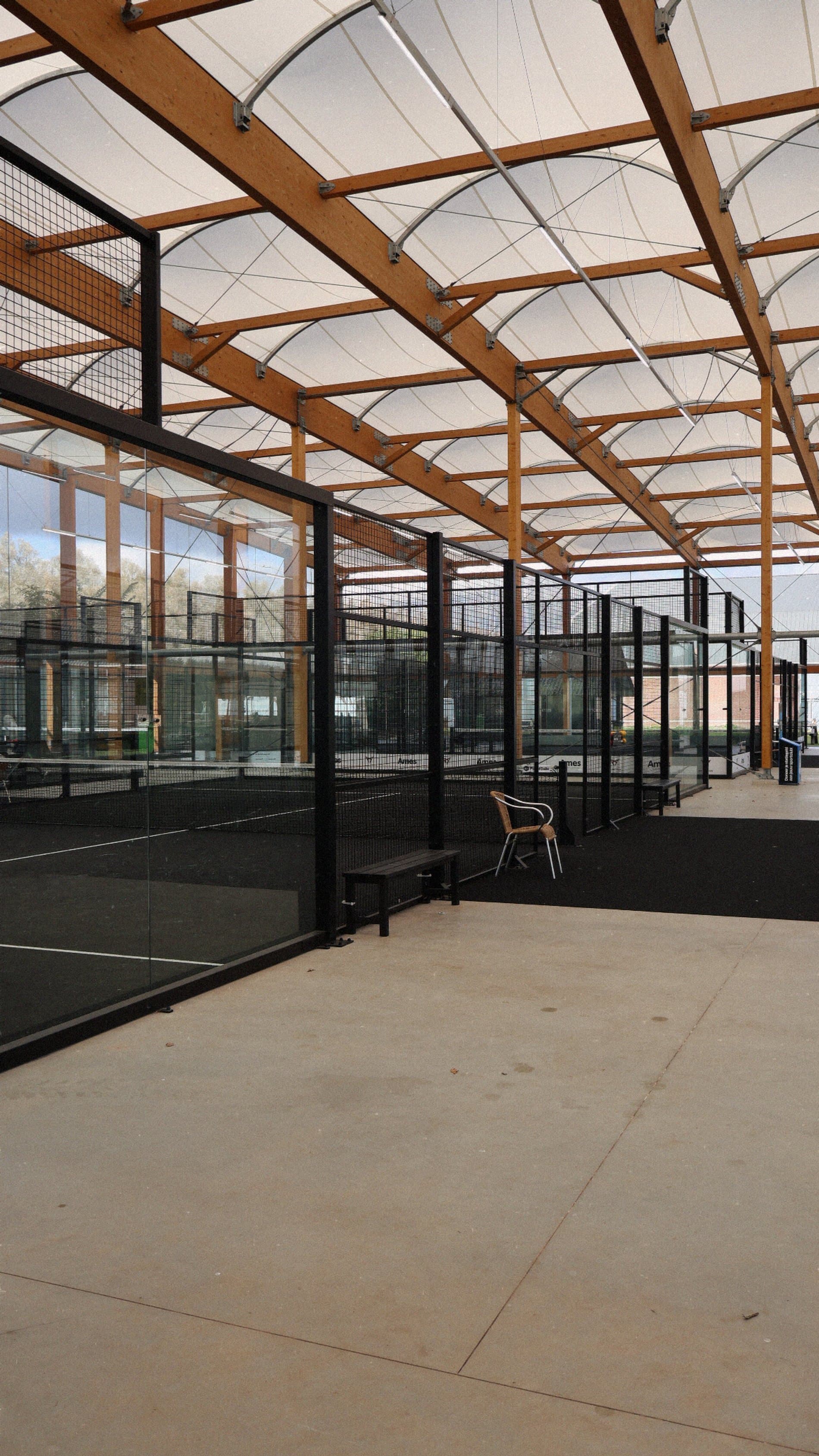 Overdekte padelbanen onder het golvende dak van TopSpinPlaza