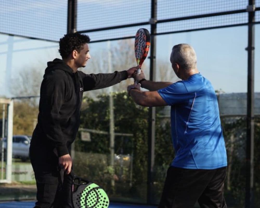 Padeltrainer legt de techniek uit op een baan van TopSpinPlaza