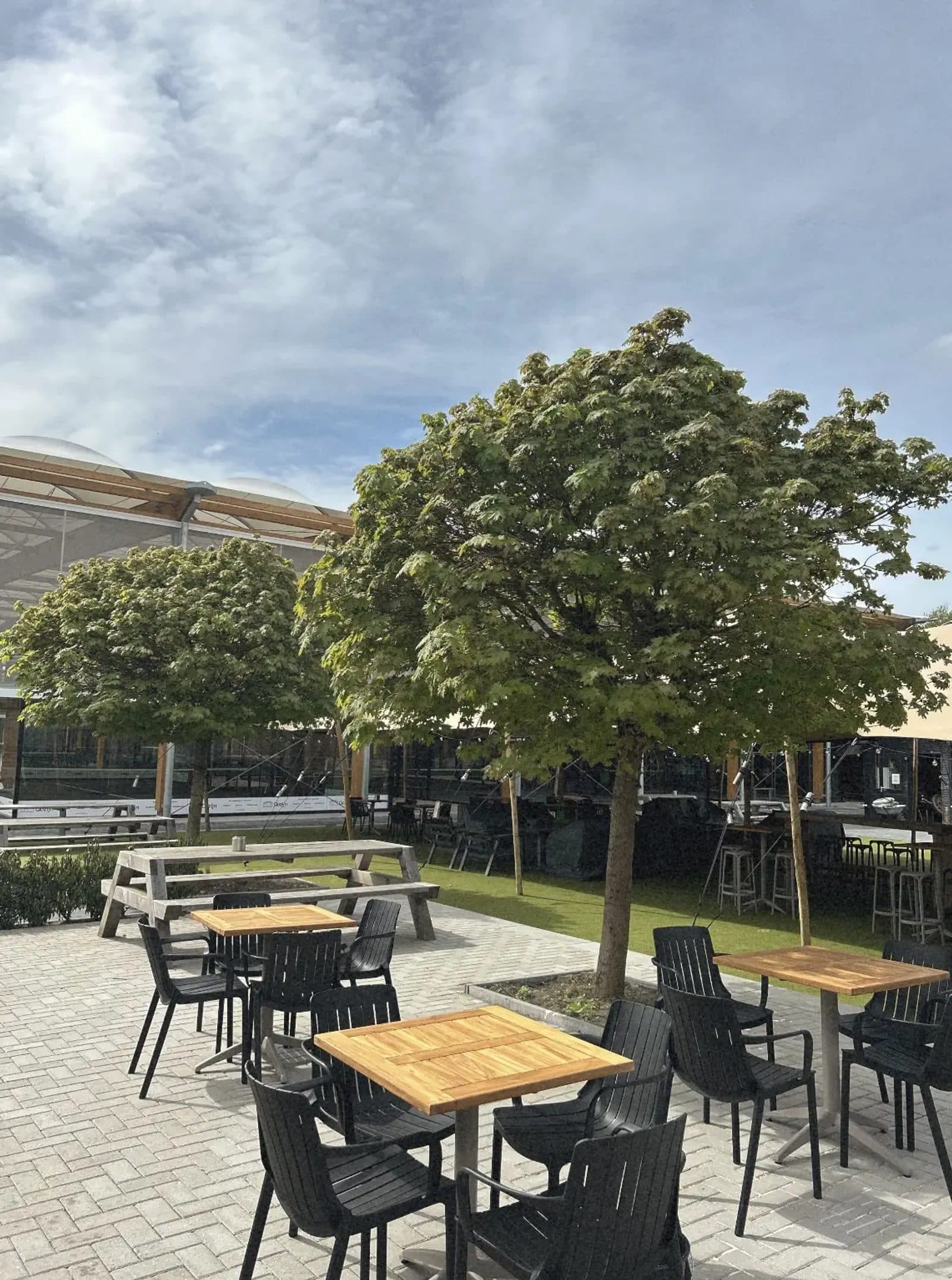 Terrastafels tussen de bomen bij de banen van TopSpinPlaza