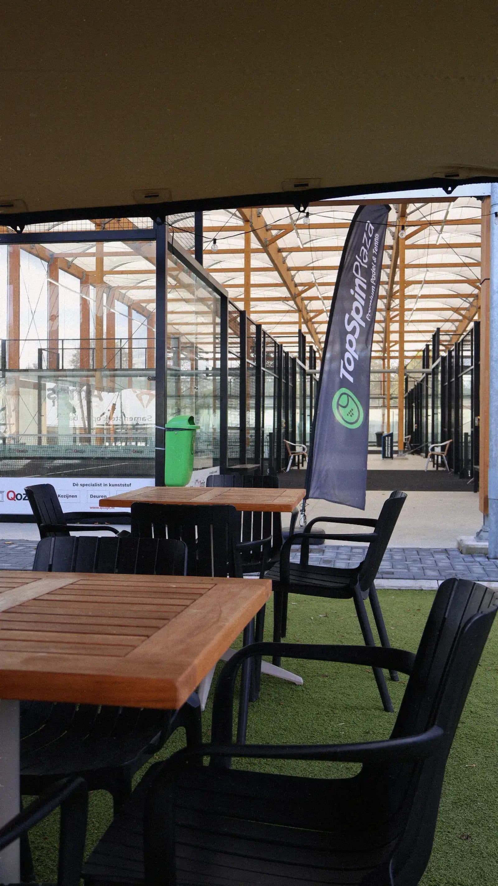 Tafels en stoelen in de plaza, direct naast de padelbanen