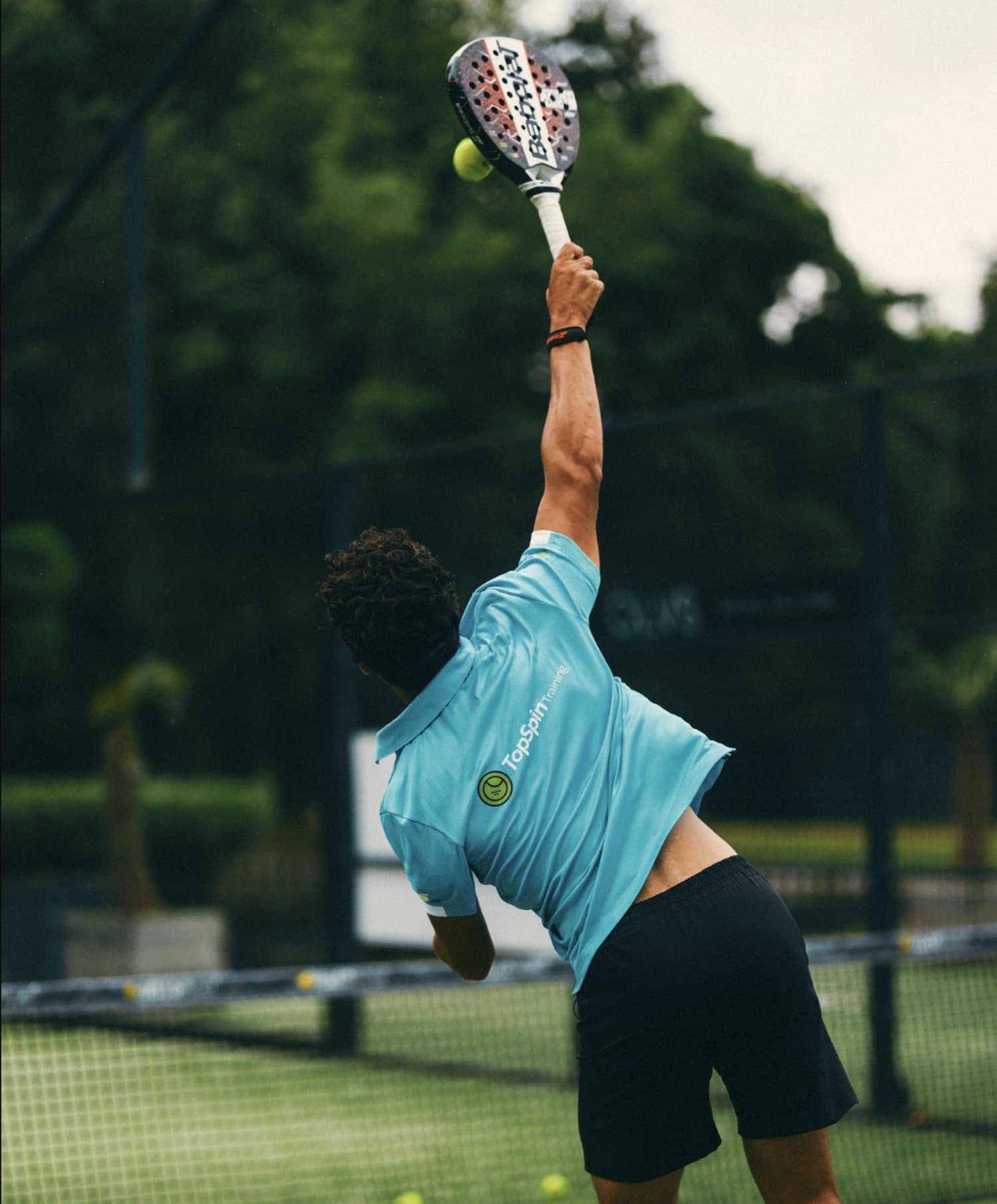 Speler slaat een smash op een padelbaan van TopSpinPlaza