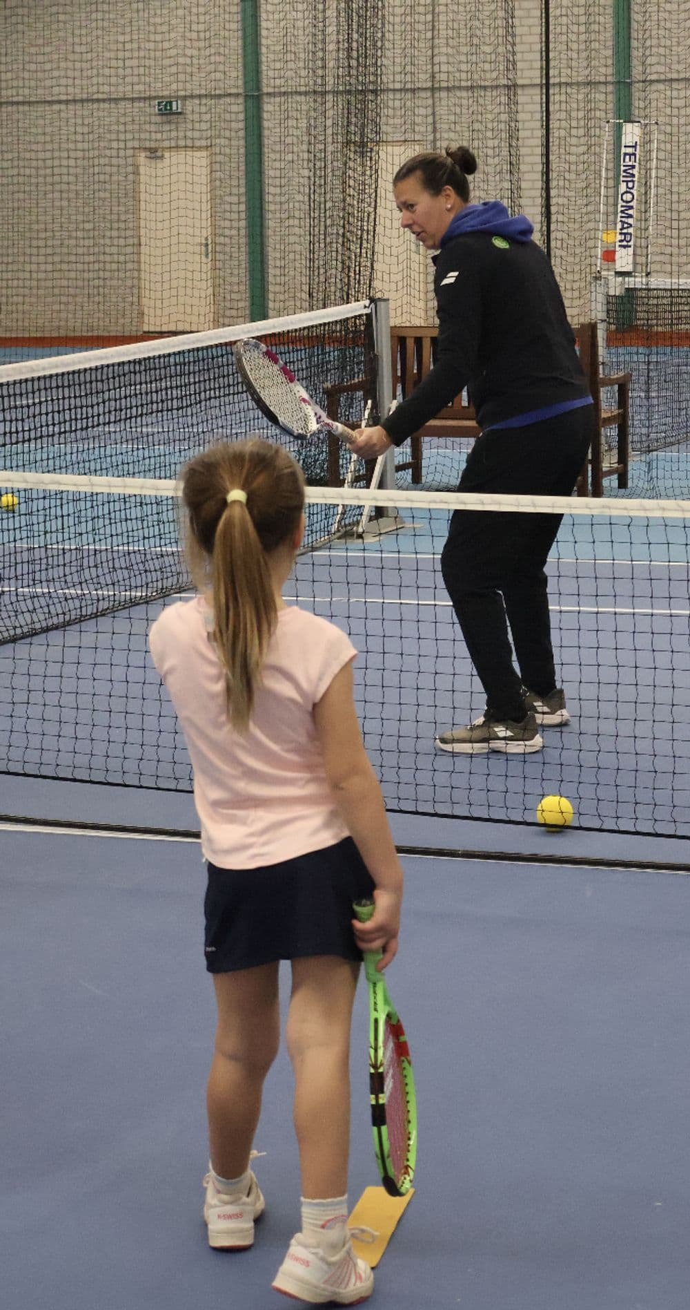 Tennisles aan het net op een indoorbaan van TopSpinPlaza
