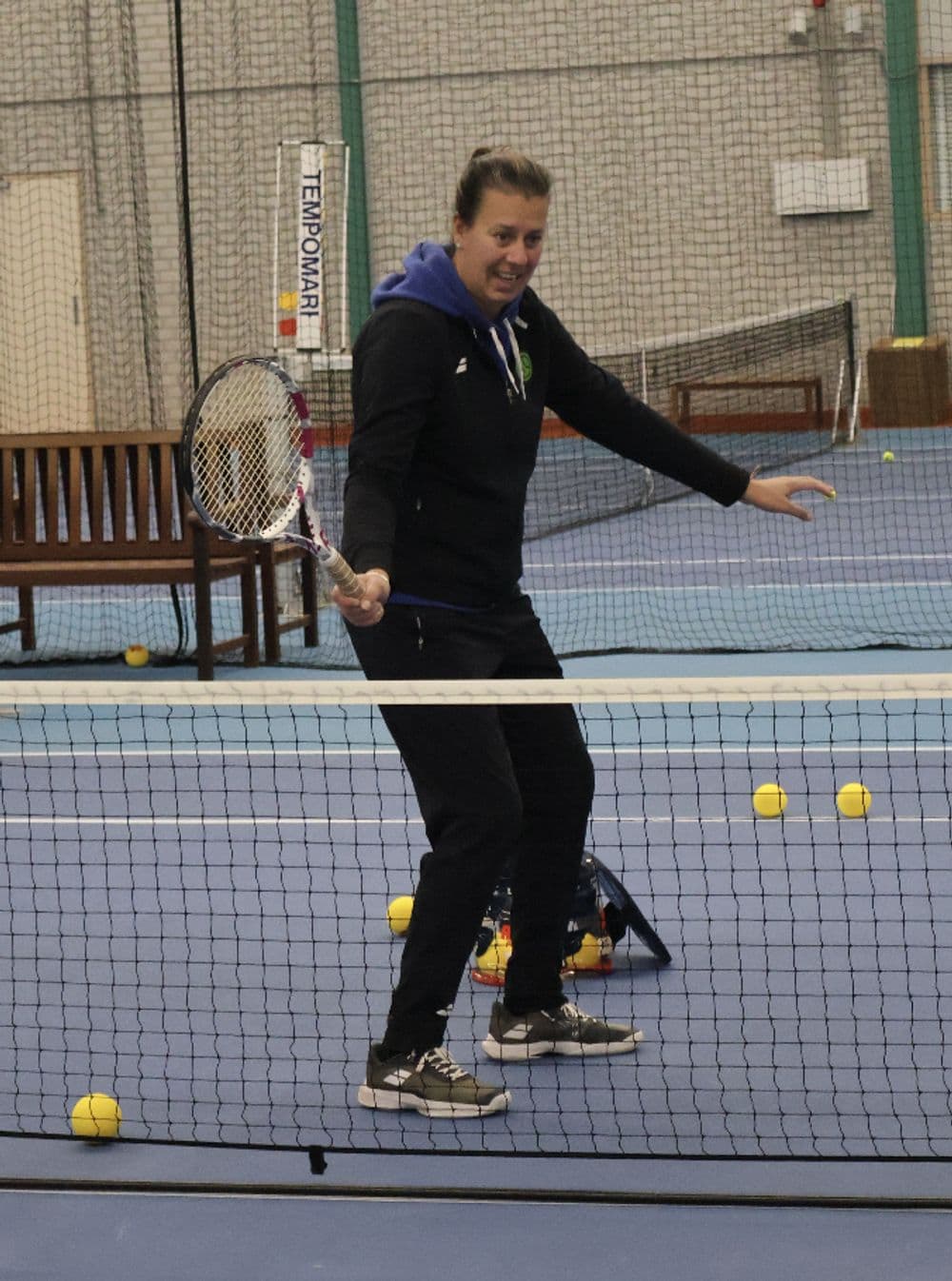 Speler slaat een forehand op een indoor tennisbaan van TopSpinPlaza