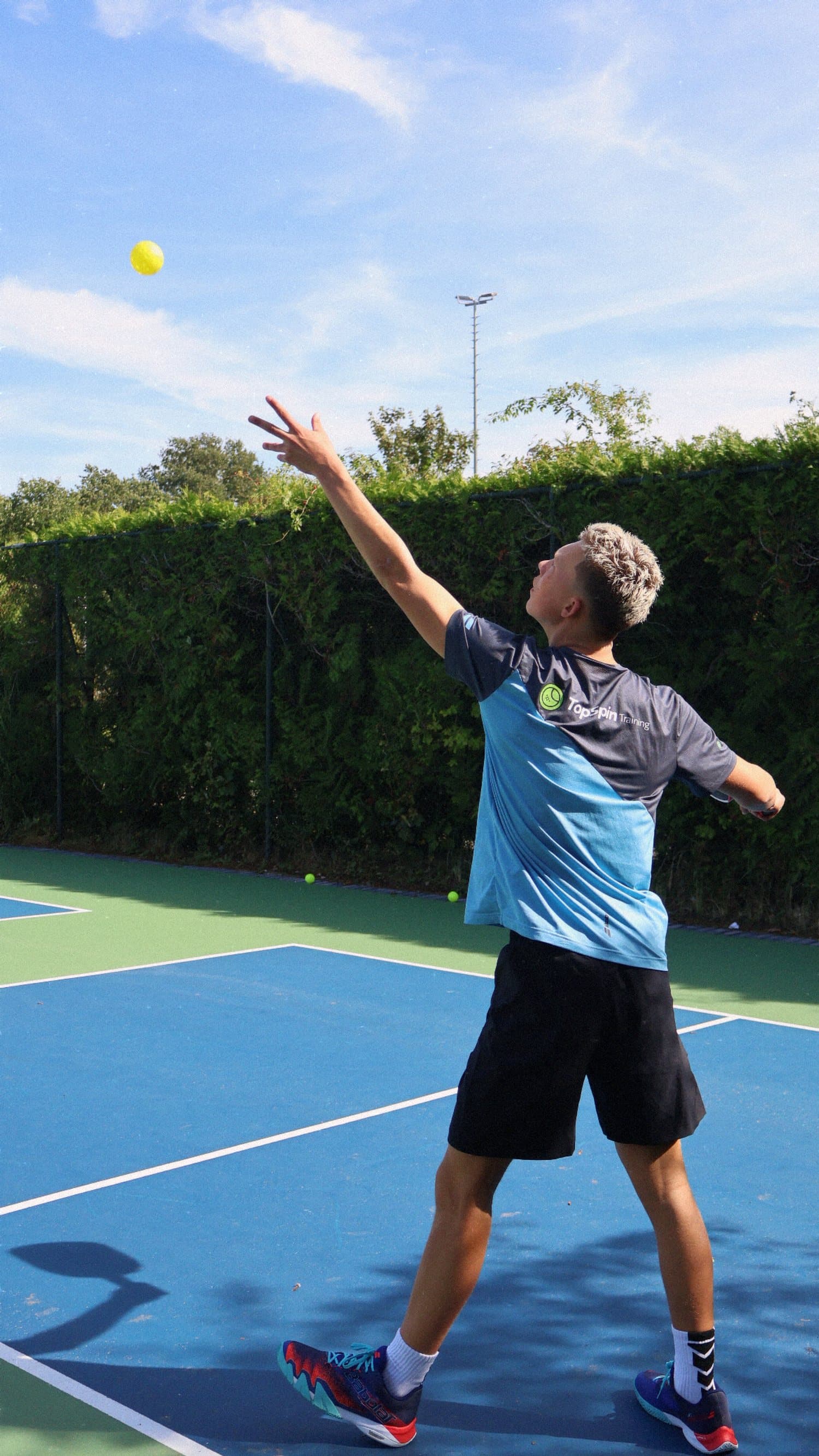 Speler serveert op een tennisbaan van TopSpinPlaza